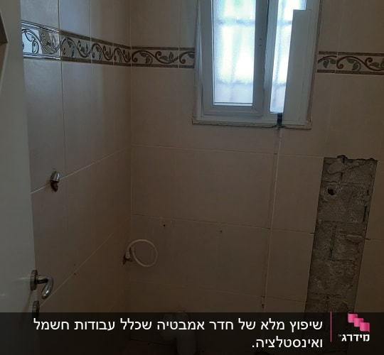 חדר אמבטיה בשיפוץ עם קיר פתוח ופסולת על הרצפה